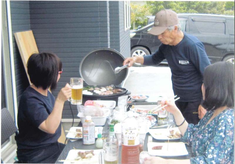 屋外のテラスで家族や仲間と一緒にバーベキューを楽しむ様子