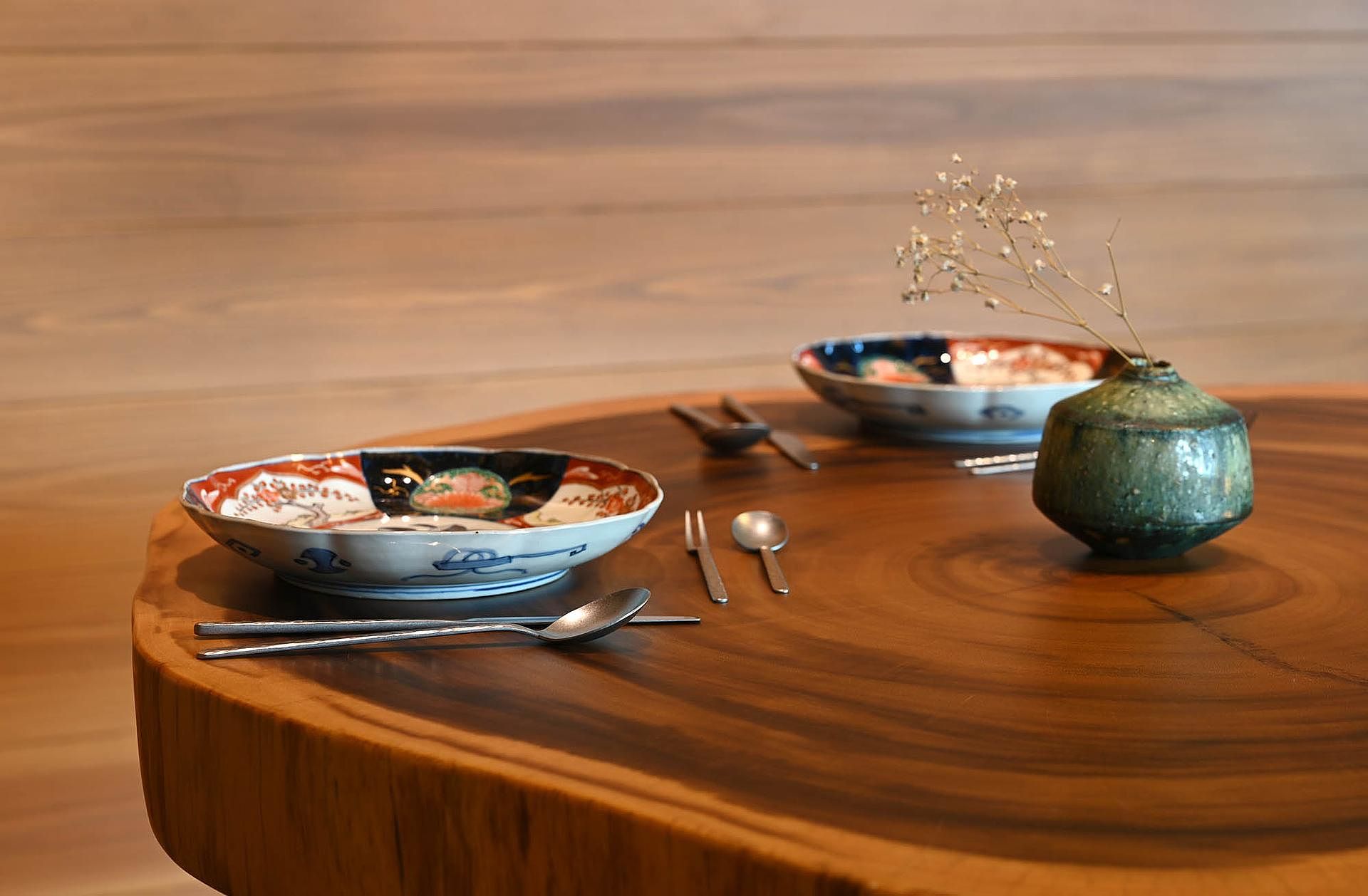 一枚板のダイニングテーブルと明治時代の食器。