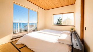 寝室1(1階):海を望む落ち着いたお部屋。シングルベッド2台をご用意しています。