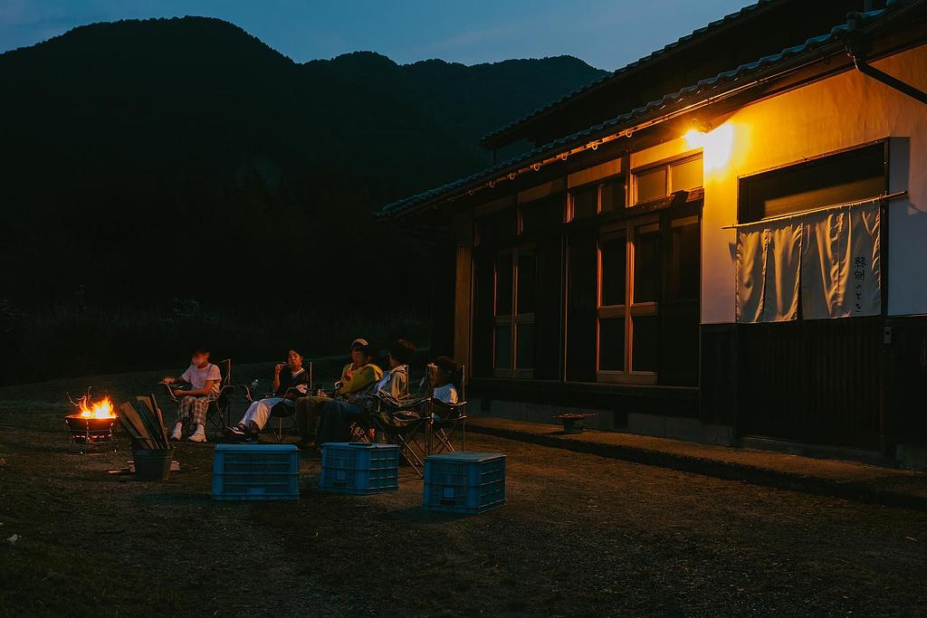 焚き火を囲んで夜を楽しむ古民家宿の風景。