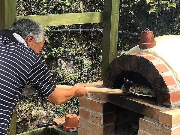 石窯でピザを焼く体験中の男性